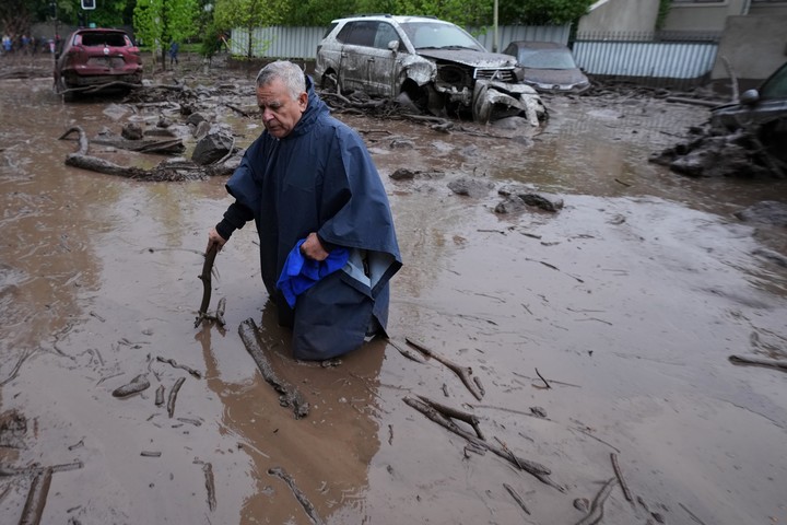 Con el agua y el barro hasta la cintura, un hombre avanza en la calle tras el aluvión en Chile. Foto AP
