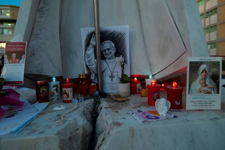 Ttarjetas y velas bajo la estatua del fallecido papa Juan Pablo II, en el exterior del hospital Gemelli —donde el papa León recibe tratamiento contra el cáncer de pulmón tras una intervención quirúrgica—, en Roma. Foto Reuters