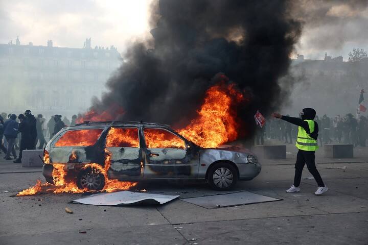 Un manifestante con el chaleco amarillo, frente a un auto incendiado en París. Foto Reuters
