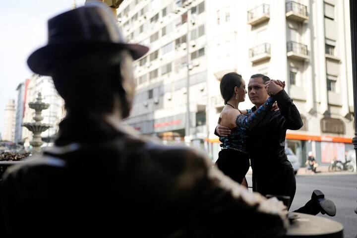 Dos bailarines de tango frente a una estatua de Gardel, en Montevideo. Foto AP/Natacha Pisarenko